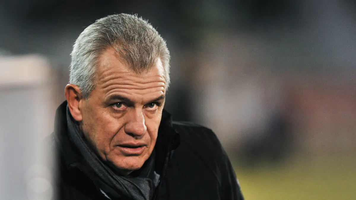 Javier Aguirre, con chamarra negra y bufanda gris, observa la cancha durante un partido de LaLiga en 2013