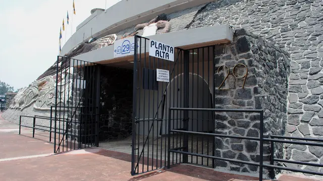 Entrada al túnel 29 del Estadio Olímpico Universitario, con reja negra, letrero de planta alta y muro de piedra volcánica