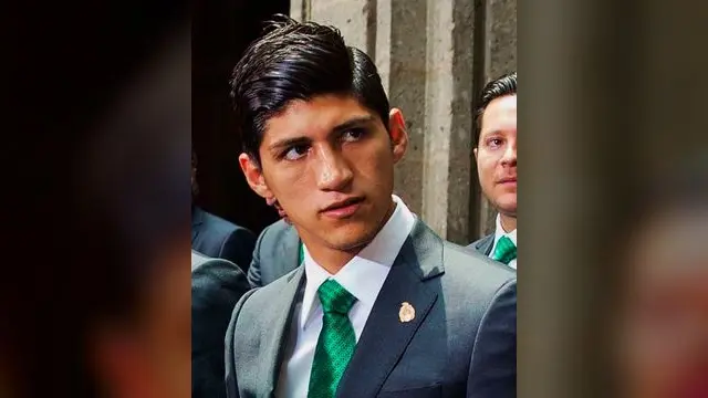 Alan Pulido con traje gris y corbata verde de la Selección Mexicana durante un acto oficial