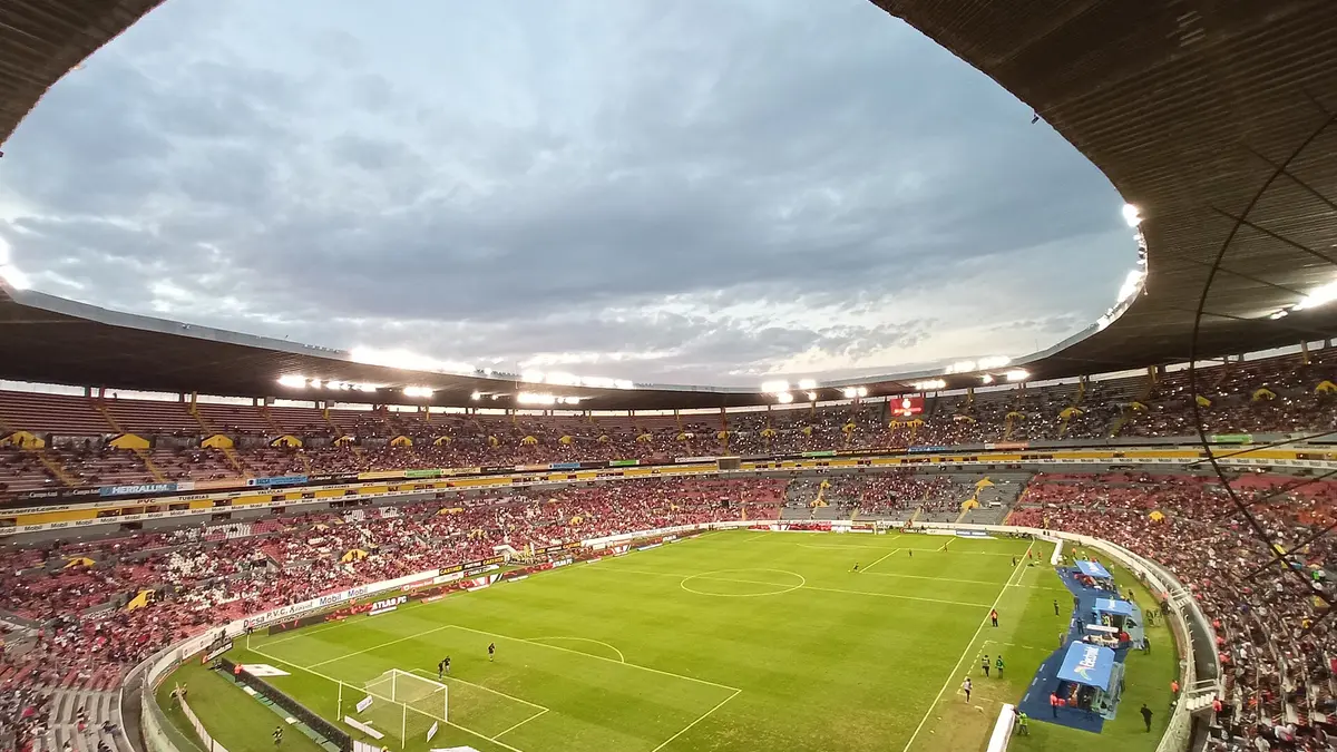Vista desde la tribuna del Estadio Jalisco de Guadalajara durante un partido, con la cancha iluminada y las gradas llenas