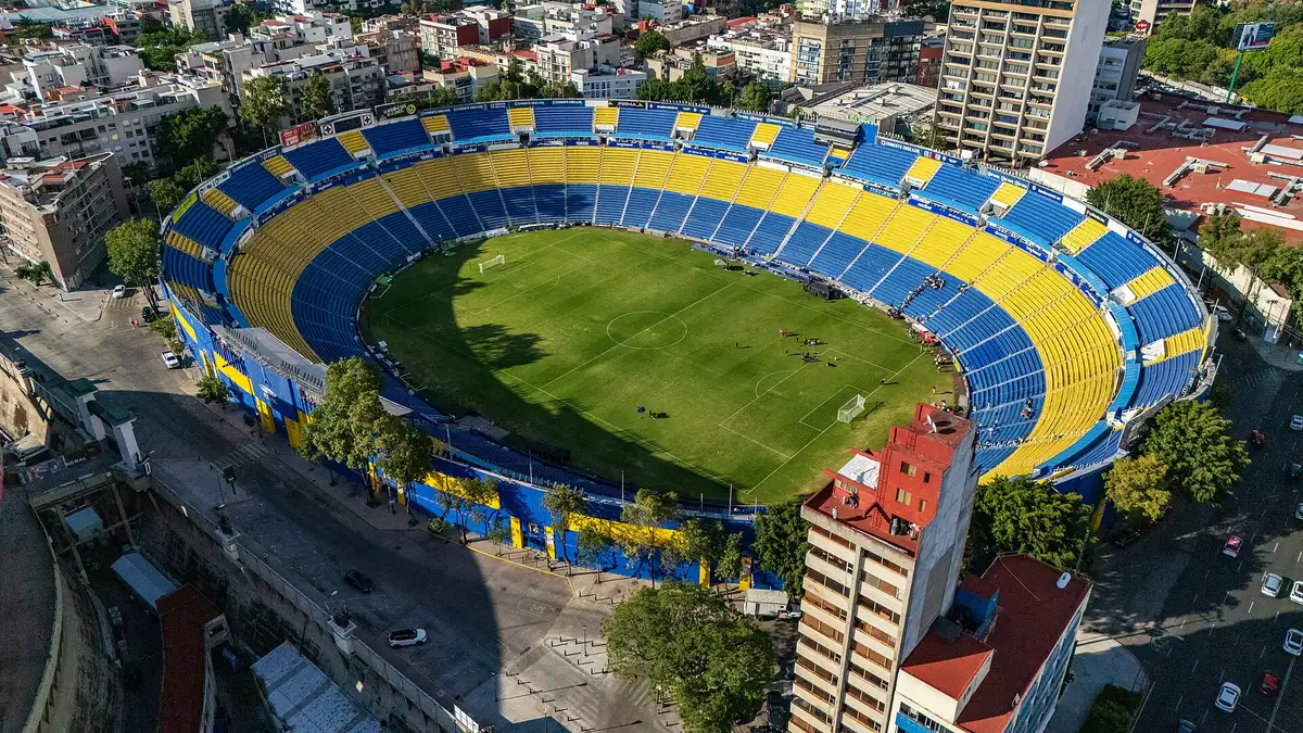 Vista aérea del Estadio Ciudad de los Deportes, con sus gradas amarillas y azules, rodeado de edificios en la Ciudad de México