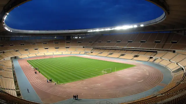 Estadio Olímpico de La Cartuja en Sevilla al anochecer, con la cancha iluminada y las gradas vacías