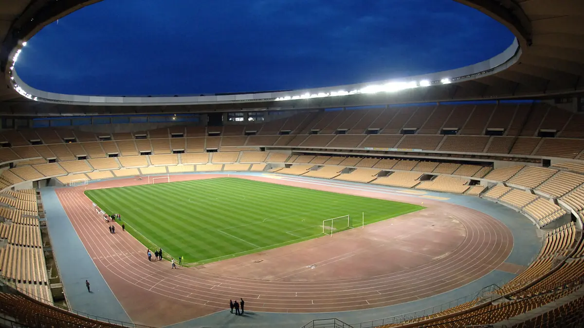 Estadio Olímpico de La Cartuja en Sevilla al anochecer, con la cancha iluminada y las gradas vacías