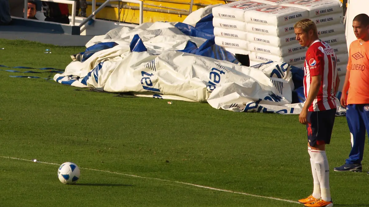 Adolfo Bofo Bautista con la playera rojiblanca de Chivas, de pie junto a la línea de banda frente a un balón