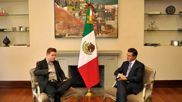 Saúl Canelo Álvarez sentado en un sillón, junto a otra persona y una bandera de México, durante su visita a la residencia oficial de Los Pinos en 2013
