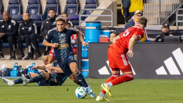 Cavan Sullivan conduce el balón con el uniforme azul marino del Philadelphia Union ante un rival de rojo del Chicago Fire en 2025