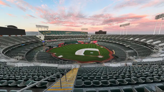 Vista desde la grada alta del Oakland Coliseum vacío al atardecer, con la cancha de pasto y el cielo rosado