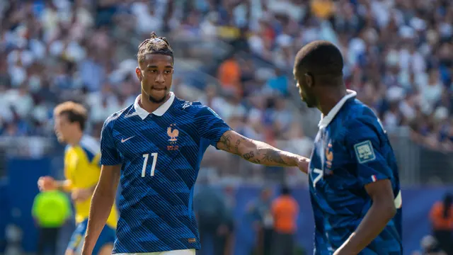 Michael Olise con el uniforme azul y el número 11 de la selección de Francia, señalando a un compañero durante un partido
