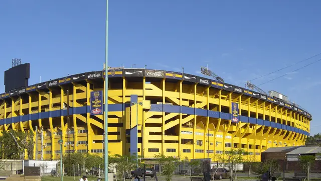 Exterior de La Bombonera, el estadio de Boca Juniors en Buenos Aires, con sus tribunas amarillas y azules bajo un cielo despejado