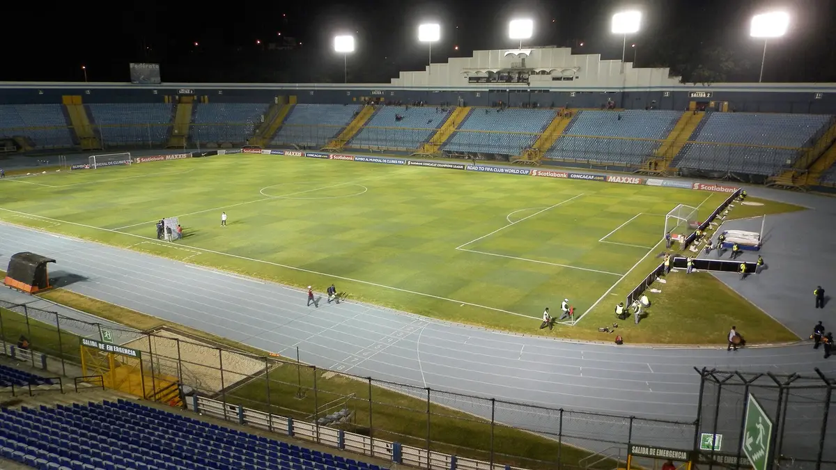 Estadio Doroteo Guamuch Flores de Ciudad de Guatemala de noche, con la cancha iluminada y las tribunas vacías