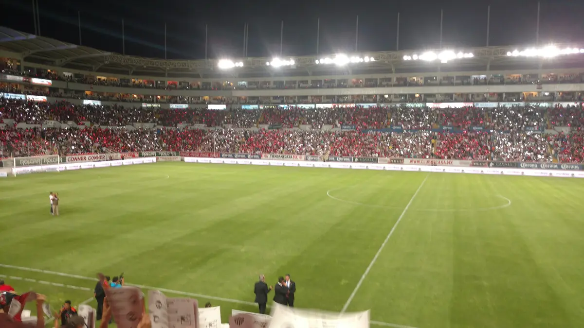 Interior del Estadio Victoria de Aguascalientes de noche, con la cancha iluminada y las gradas llenas de aficionados