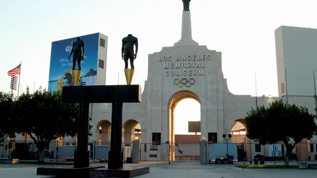Entrada principal del Los Angeles Memorial Coliseum con sus aros olímpicos, su pebetero y dos estatuas de bronce al amanecer