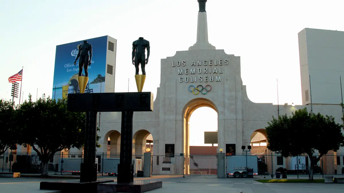 Entrada principal del Los Angeles Memorial Coliseum con sus aros olímpicos, su pebetero y dos estatuas de bronce al amanecer