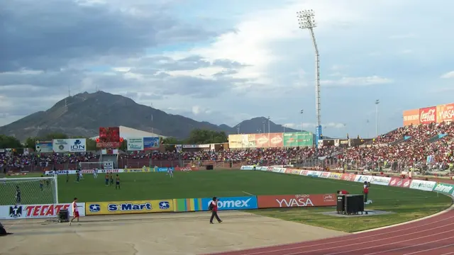 Vista del Estadio Olímpico Benito Juárez de Ciudad Juárez durante un partido, con la cancha, la pista de atletismo, las gradas llenas y un cerro al fondo