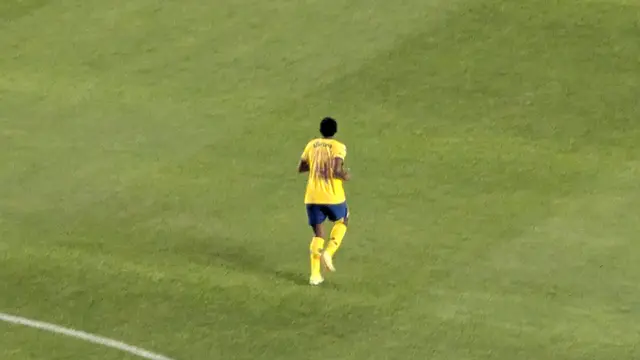 Una jugadora del América Femenil con uniforme amarillo y azul corre sola sobre el césped durante un partido ante Pachuca
