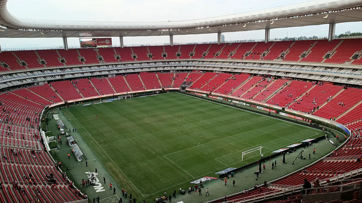 Interior del Estadio Akron de Guadalajara, casa de Chivas, con gradas rojas vacías y la cancha vista desde lo alto