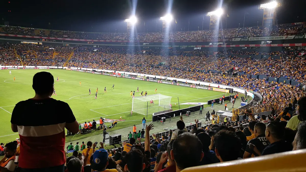 Partido de semifinal entre Tigres Femenil y Rayadas en el Estadio Universitario, de noche, con las gradas llenas de aficionados