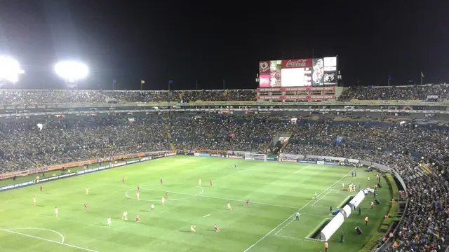 Estadio Universitario de Tigres en San Nicolás de los Garza lleno de noche durante un partido, con la cancha iluminada y el marcador electrónico al fondo