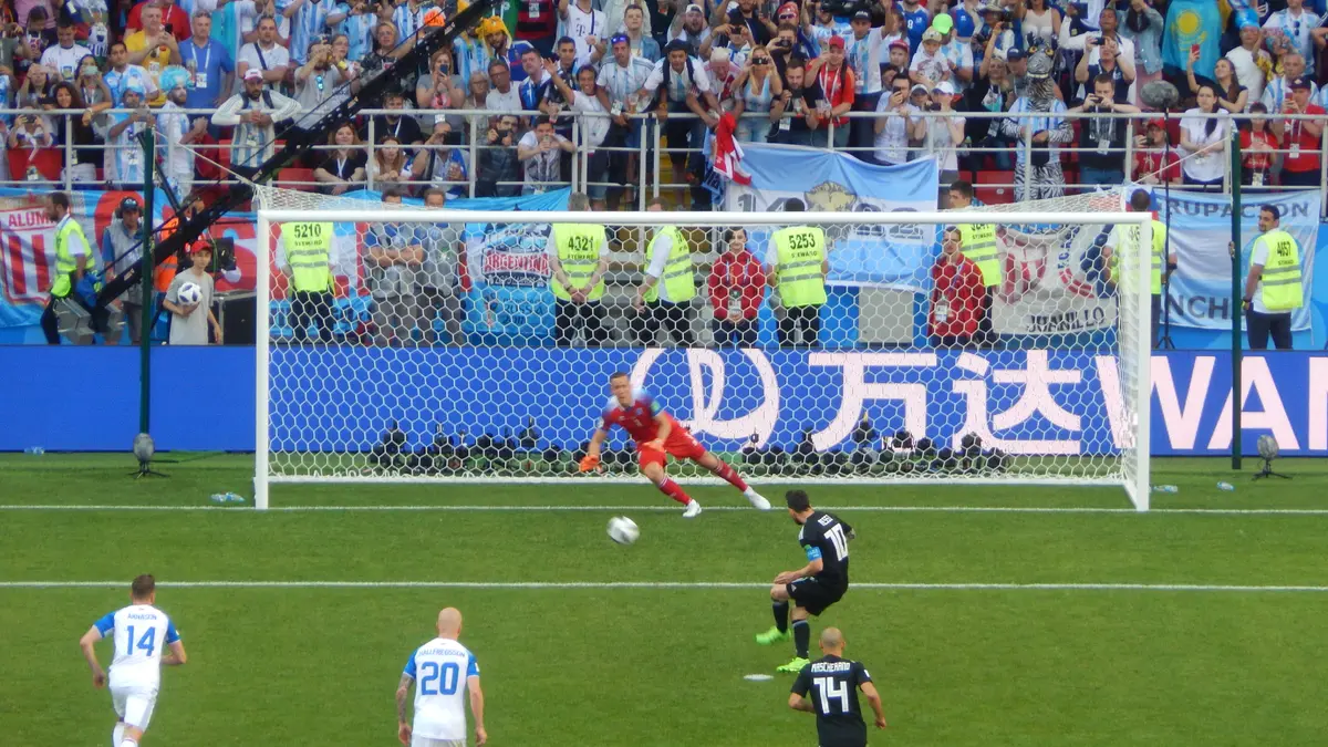 Lionel Messi cobra un penal con la camiseta oscura de Argentina ante Islandia en el Mundial de Rusia 2018, mientras el portero se lanza y la tribuna llena observa