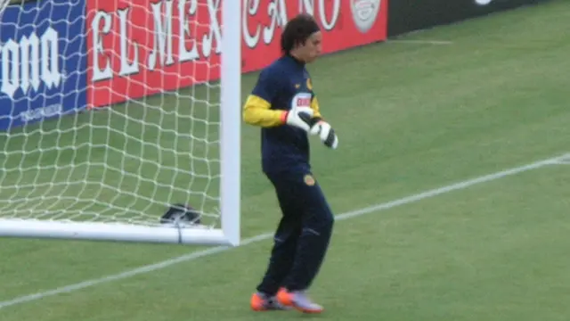 Guillermo Ochoa con ropa de entrenamiento del Club América calienta junto a la portería antes de un amistoso en 2010
