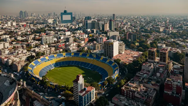 Vista aérea del Estadio Ciudad de los Deportes, con gradas azules y amarillas, rodeado de edificios de la Ciudad de México