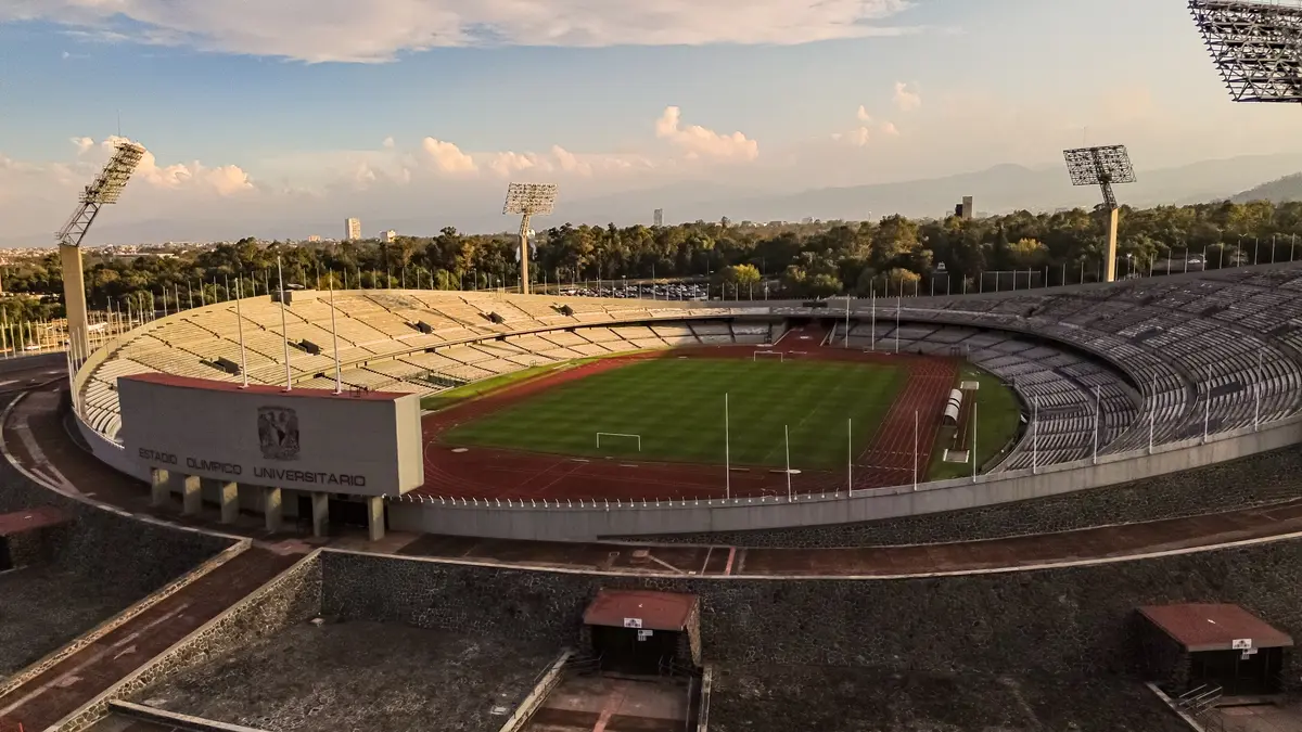 Vista aérea del Estadio Olímpico Universitario en Ciudad Universitaria, con la cancha, la pista de atletismo y las gradas vacías al atardecer