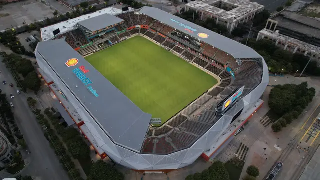 Vista aérea del Shell Energy Stadium de Houston al anochecer, con la cancha iluminada y las gradas vacías