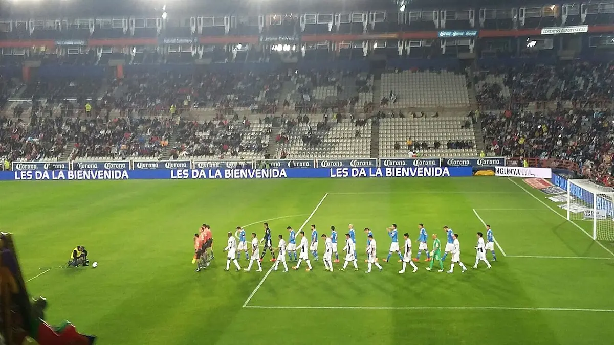 Jugadores de Cruz Azul con uniforme azul y de Pachuca de blanco saludan en fila antes de un partido en el Estadio Hidalgo