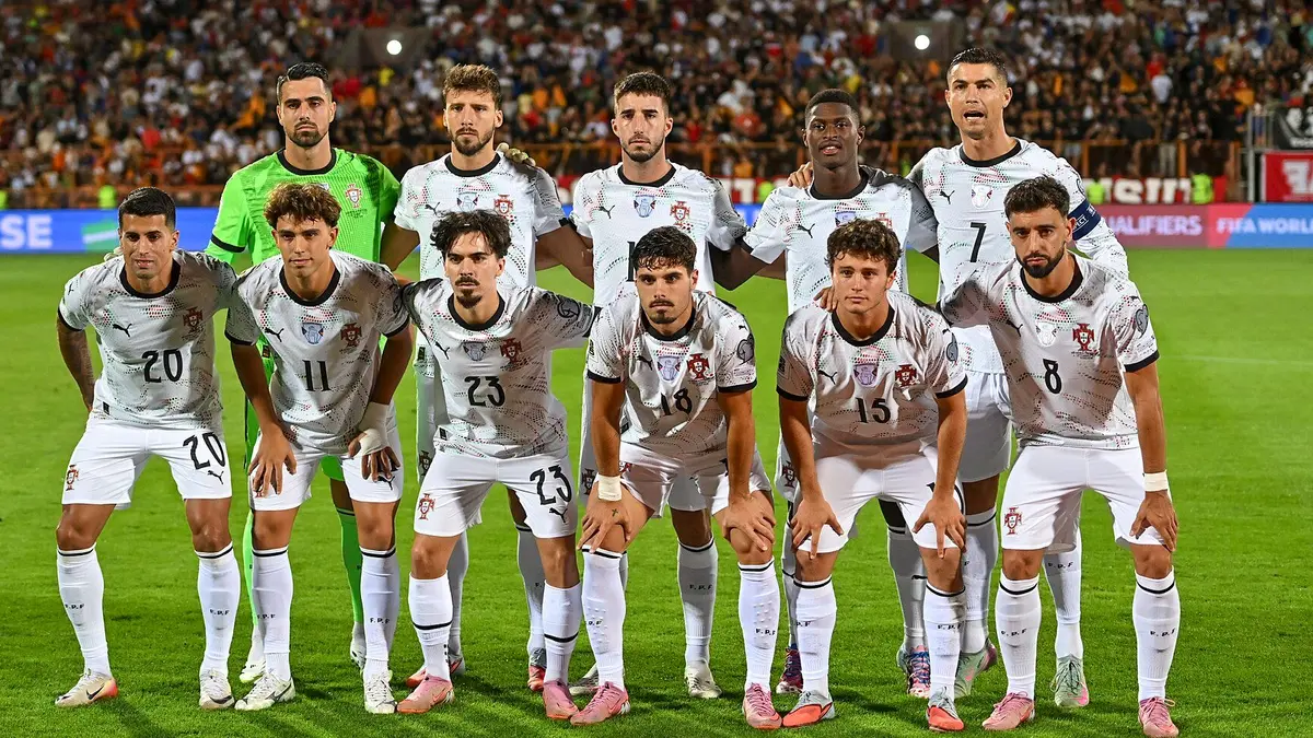 Foto de equipo de la selección de Portugal con uniforme blanco antes de un partido, con Cristiano Ronaldo de pie en la fila de atrás y Bruno Fernandes al frente