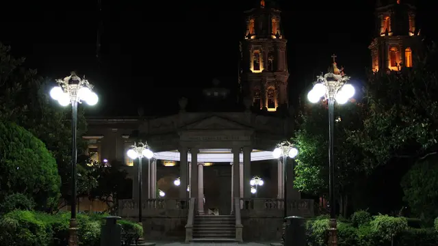 Kiosco iluminado de la Plaza de Armas de San Luis Potosí de noche, con faroles encendidos y las torres de la catedral al fondo