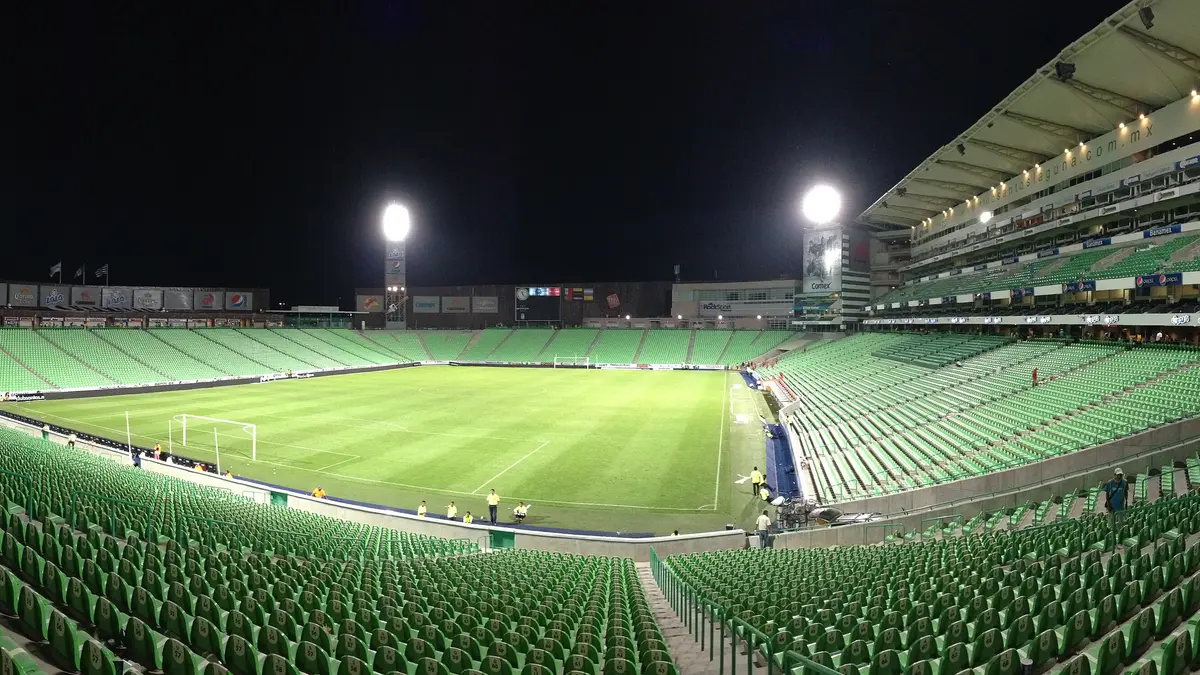 Vista panorámica nocturna del Estadio Corona de Torreón, casa de Santos Laguna, con las gradas verdes vacías y la cancha iluminada