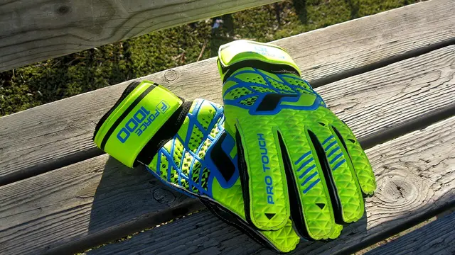 Par de guantes de portero de color verde fosforescente sobre una banca de madera al sol