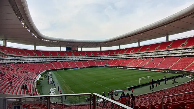 Interior del Estadio Akron de Guadalajara con las tribunas rojas casi vacías y la cancha al fondo después de un partido