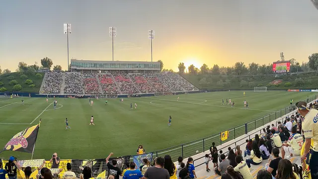 Aficionados del América Femenil en la tribuna del Titan Stadium al atardecer durante un partido ante Angel City en 2024
