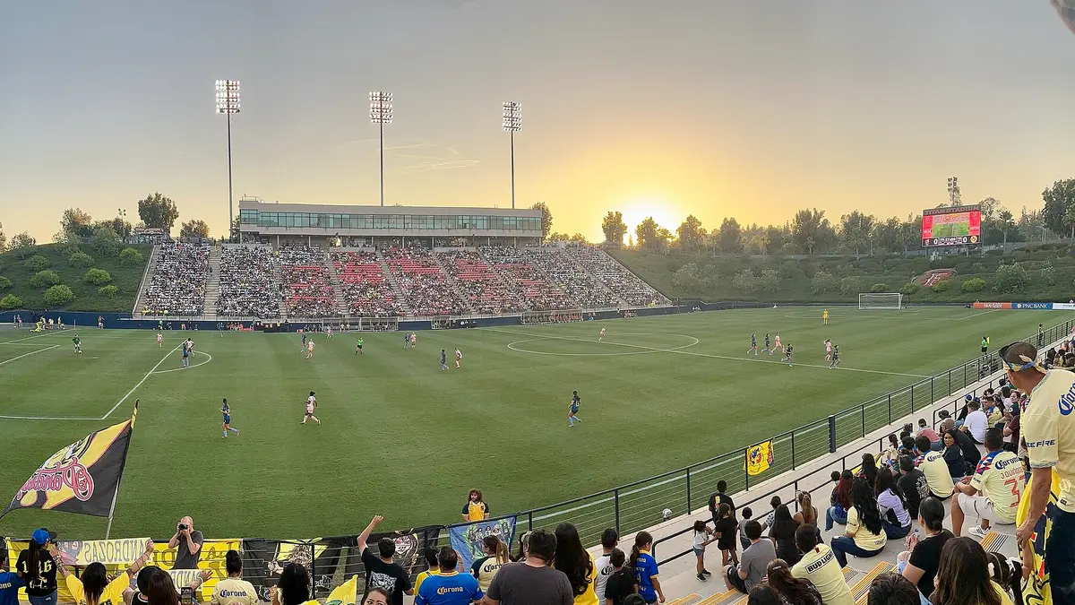 Aficionados del América Femenil en la tribuna del Titan Stadium al atardecer durante un partido ante Angel City en 2024